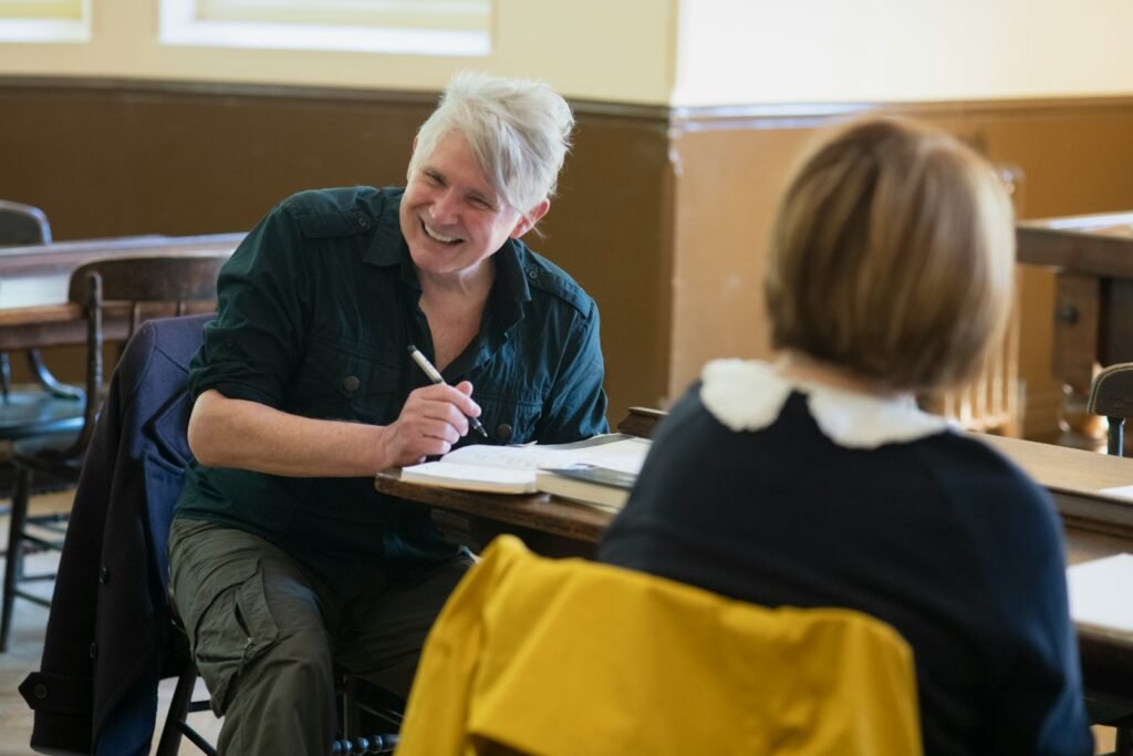 a woman sitting at a table with a notebook and pen