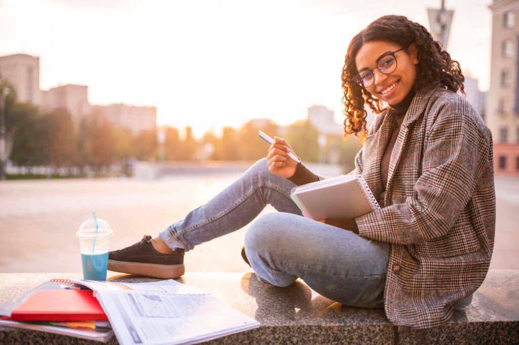 Smiley woman doing homework outdoors
